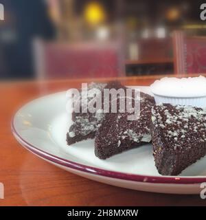 Black bread croutons with garlic. Beer snack. Fried rye bread sprinkled with garlic and sauce on a ceramic plate on a table in a pub. Stock Photo