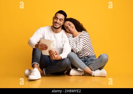 Online Entertainment. Happy Young Middle Eastern Couple Using Digital Tablet Together Stock Photo