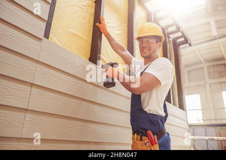 Cheerful builder using cordless electric drill at construction site Stock Photo