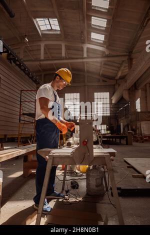 Handsome male worker using woodworking machine in workshop Stock Photo