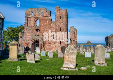 Lindisfarne Priory from the churchyard of St Mary’s Parish Church in Lindisfarne Village on Holy Island on the Northumberland Coast of England, UK Stock Photo