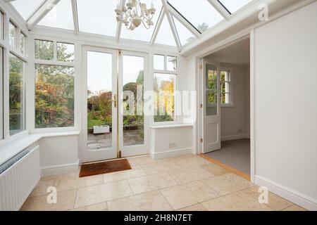Cambridgeshire, England - November 4 2019: Vacant conservatory, garden room, within British home with doors opening to garden and patio Stock Photo
