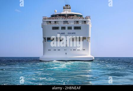 Wake of the cruise ship 'Island Escape' in navigation in turquoise waters, ships trace, view on the square stern and funnel, sailing at sea Stock Photo