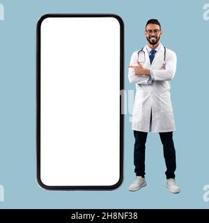 Doctor pointing at big white empty smartphone screen, mock-up Stock Photo