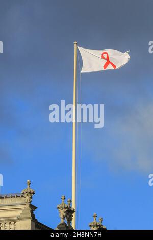 Westminster, London, UK. 01st Dec, 2021. A flag with a red ribbon can be seen on a government building in Westminster for World Aids day today. Credit: Imageplotter/Alamy Live News Stock Photo