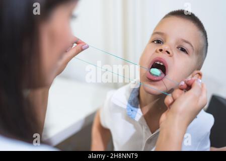 A beautiful woman speech therapist deals with the boy and teaches him the correct pronunciation and competent speech. Stock Photo