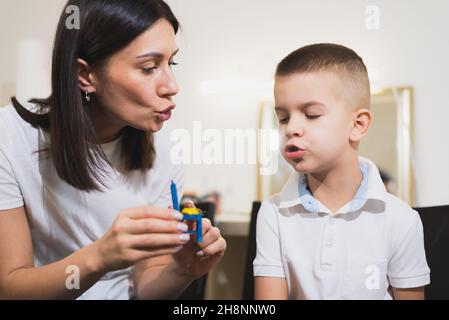 A beautiful woman speech therapist deals with the boy and teaches him the correct pronunciation and competent speech. Stock Photo