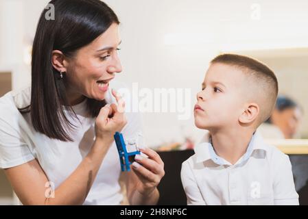 A beautiful woman speech therapist deals with the boy and teaches him the correct pronunciation and competent speech. Stock Photo