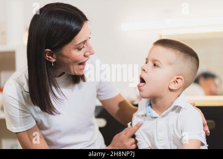 A beautiful woman speech therapist deals with the boy and teaches him the correct pronunciation and competent speech. Stock Photo