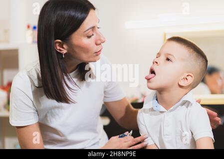 A beautiful woman speech therapist deals with the boy and teaches him the correct pronunciation and competent speech. Stock Photo