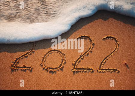 Happy New Year 2022 concept, lettering on the beach. Sea sunrise. Stock Photo