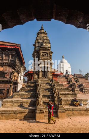 A woman with her baby walks by the Siddhi Laxmi Hindu temple in Durbar Square. Medieval Newar city of Bhaktapur, Nepal. Stock Photo