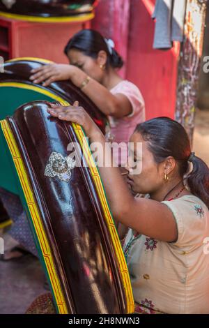 Two women painting Tibetan ritual drums in an outdoor workshop in Kathmandu, Nepal. Stock Photo