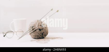 Knitting needles with threads, beige yarn. Hobby for women concept.  Knitting accessories Stock Photo by paralisart