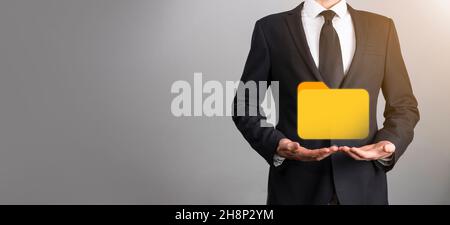 Businessman hold folder icon.Document Management System or DMS setup by IT consultant with modern computer are searching managing information and corp Stock Photo