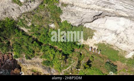 Dangerous wooden walkway hanging alongside a vertical cliff. Extremely dangerous footpath on a cliff wall to Seganing Waterfall. Rocky cliff and Stock Photo