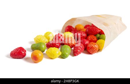 Colorful candies in the form of fruits scattered from a paper bag on a white background. Stock Photo