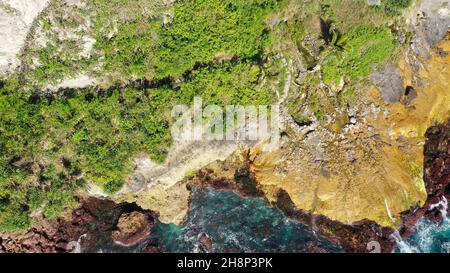 Dangerous wooden walkway hanging alongside a vertical cliff. Extremely dangerous footpath on a cliff wall to Seganing Waterfall. Rocky cliff and Stock Photo