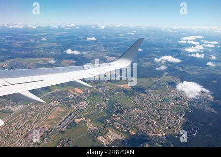 Airplane window view showing wing of the plane flying over small town city Stock Photo