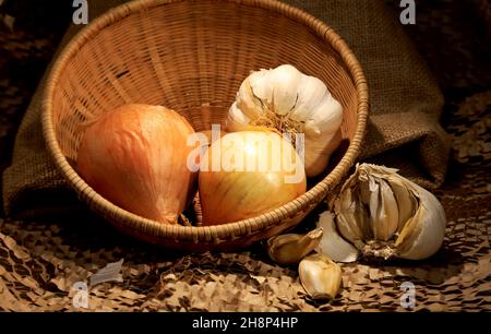 Onion and garlic on a table with a small brown basket Stock Photo