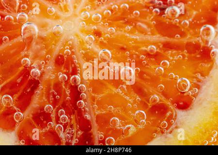 Grapefruit close-up in liquid with bubbles. Slice of blood red ripe grapefruit in water. Part of set. Stock Photo