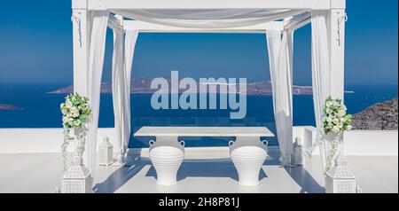 Santorini Island, Greece. Wedding decoration on a popular couple destination. Elegant wedding arch with white flowers, vases on background of blue sea Stock Photo