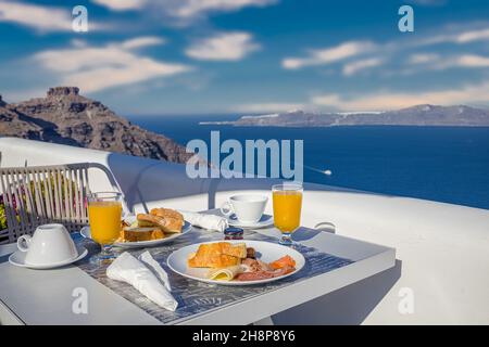 Morning fresh juice and breakfast with blue sea view. Couple traveling and honeymoon destination, idyllic morning scenic bright caldera view in Greece Stock Photo