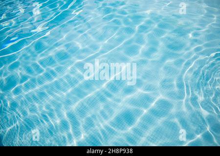 Surface of blue swimming pool. Summer water sport, recreational background. Texture of water surface, blue turquoise vivid bright sunny day closeup. Stock Photo