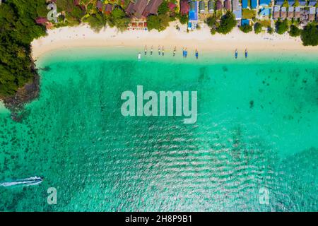 View from above, stunning aerial view of a beautiful tropical beach with white sand and turquoise clear water, long-tail boat and people sunbathing,Lo Stock Photo