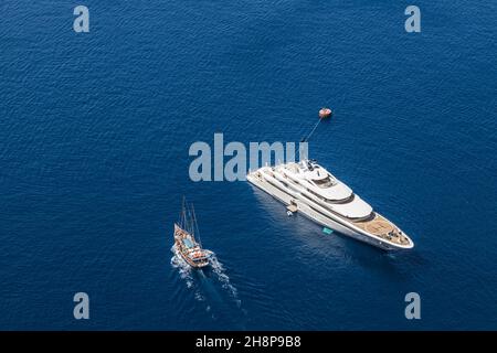 Aerial drone top down photo of luxury exotic yacht with wooden deck anchored in Aegean island with deep blue sea, Greece. Stock Photo