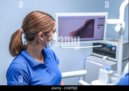 Dental assistant examining an x-ray on the monitor. Dentist assistant looking at monitor with x-ray of teeth. Stock Photo