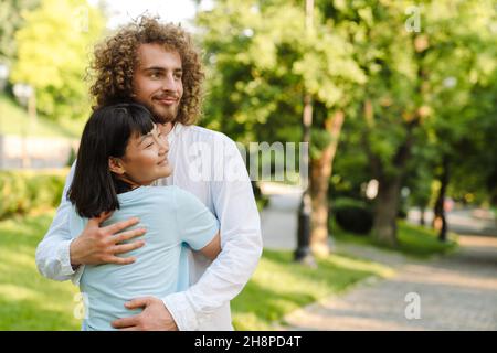 Happy young multiethnic couple cuddling embracing together in the green park Stock Photo