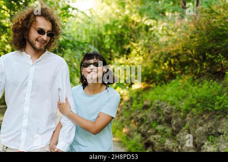 Happy young multiethnic couple cuddling embracing together in the green park Stock Photo