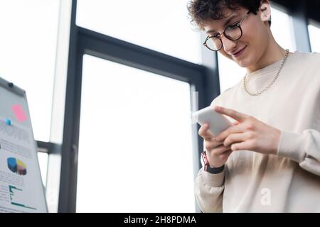 Low angle view of young businessman using mobile phone near flip chart in office,stock image Stock Photo