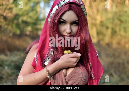 Female model in forest, daytime photo session. Young woman with red hairs, princess with frog. Stock Photo