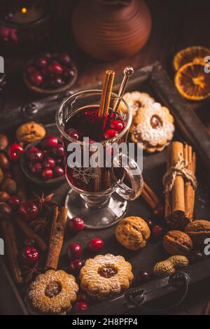 Mulled wine with cranberry and spices, Christmas cookies and candles Stock Photo