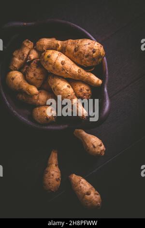 Raw topinambour in bowl on wooden background Stock Photo