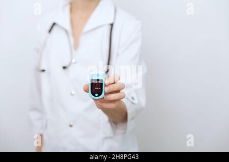 Pulse oximeter with hand of doctor isolated on white. Measuring oxygen saturation, pulse rate and oxygen levels. The concept of portable digital Stock Photo