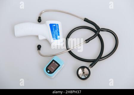 Stethoscope, pulse oximeter and thermometer gun on white background. Phonendoscope. Infrared isometric thermometer gun to check body temperature for Stock Photo