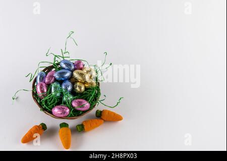 Orange carrots and a filled Easter basket with sweet eggs Stock Photo