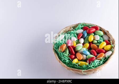a filled Easter basket with sweet eggs on a light background Stock Photo