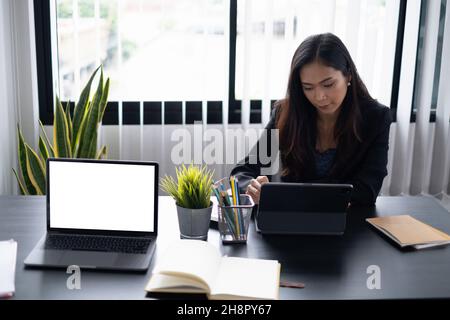 Portrait of cheerful asian woman with casual life on desk in home office. Concept of young business people working at home. Stock Photo