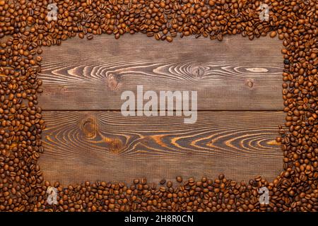 rectangular frame of many roasted coffee beans on brown wooden surface Stock Photo