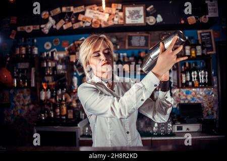 Focused woman bartender intensely finishes his creation in pub Stock Photo