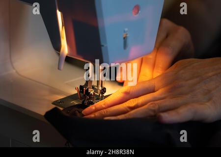 woman's hands sew on a sewing machine, close up, working process Stock Photo