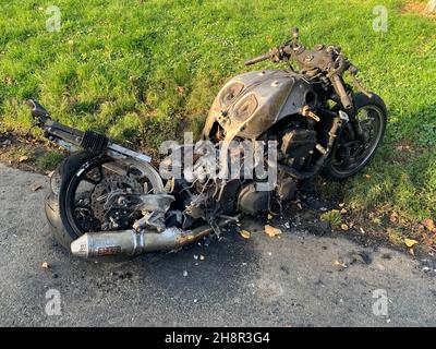 Motorbike se on fire Northampton UK burnt stolen thieves kids old fire petrol tank left by the side of the road cables melt melted petrol tarmac damage Stock Photo