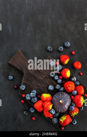Fresh strawberries, blueberries and figs, on dark background, top view Stock Photo