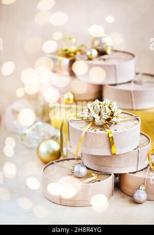 Christmas or New year round kraft gift boxes, gold holiday balls on a bokeh background of twinkling party lights of garland, copy space Stock Photo