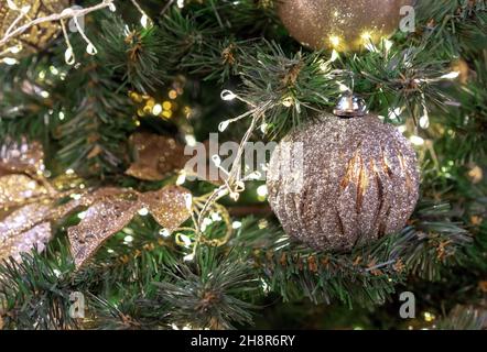 Gold-colored Christmas ball with silver plating on the Christmas tree. Stock Photo