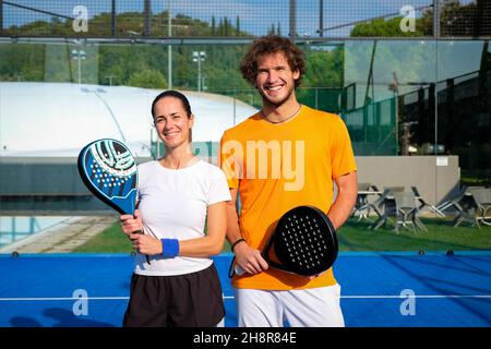 Portrait of two smiling sportsman's posing on padel court outdoor with rackets - Padel players looking at camera after win a padel match Stock Photo
